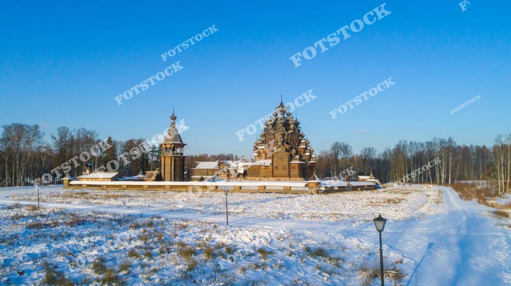 На фотографии изображена Покровская церковь, расположенная в Невском лесопарке в Ленинградской области. Этот деревянный храм выполнен в традиционном русском стиле и гармонично сочетается с заснеженным зимним пейзажем. Окружающие постройки и лесная природа подчеркивают спокойствие и величие святыни. Покровская церковь является уникальным образцом русской деревянной архитектуры, привлекающей туристов и паломников круглый год.